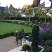 Blick von einer Terrasse auf Büsche und Bäume in unteren Teil des Gartens
